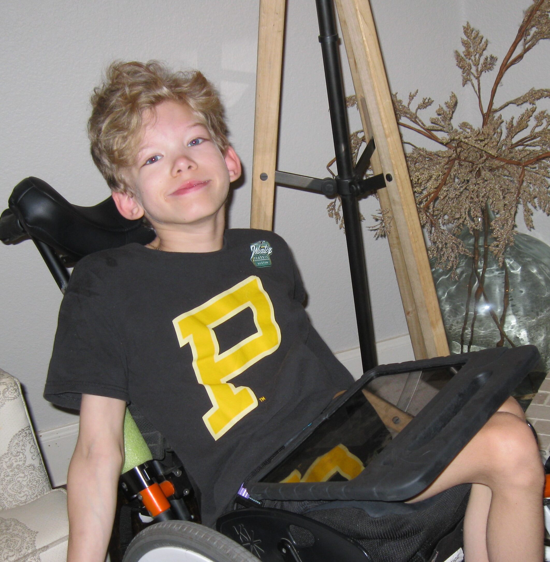 A boy in a wheelchair with a bag on his back.